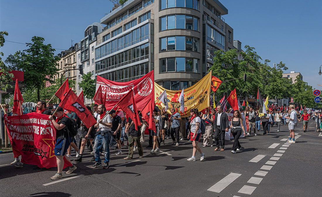 Demonstrationszug am Ersten Mai mit roten Fahnen und Transparenten