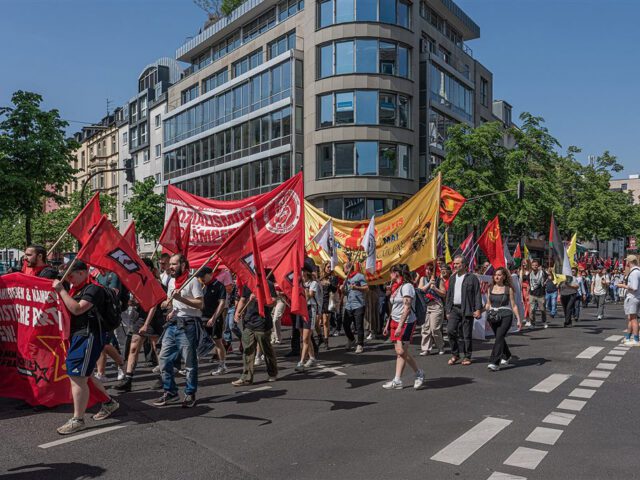 Demonstrationszug am Ersten Mai mit roten Fahnen und Transparenten